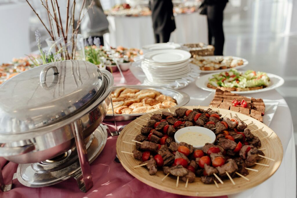 Elegant buffet featuring skewered meats, fresh salads, and assorted desserts at a festive event.